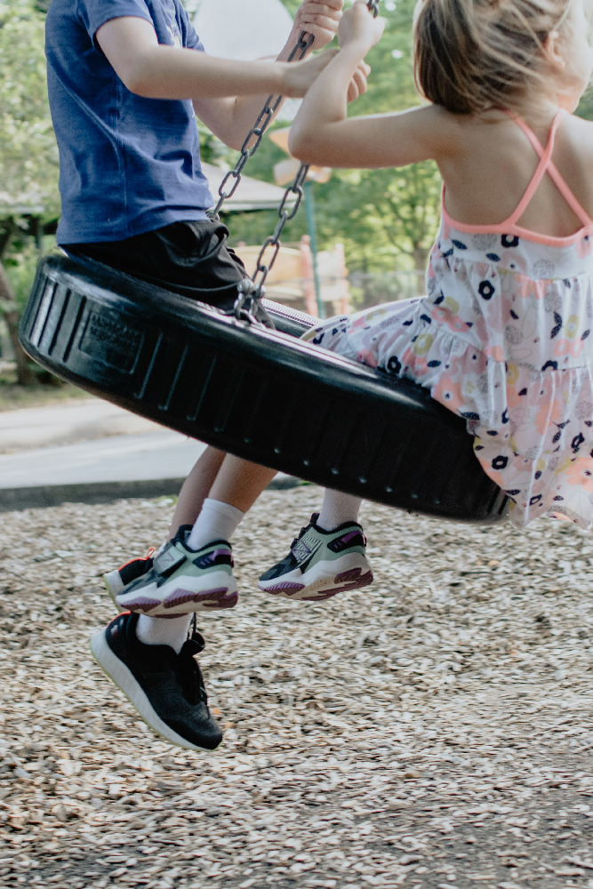 Children playing together on a commercial tire swing designed to provide multi-directional swinging motion and group play.